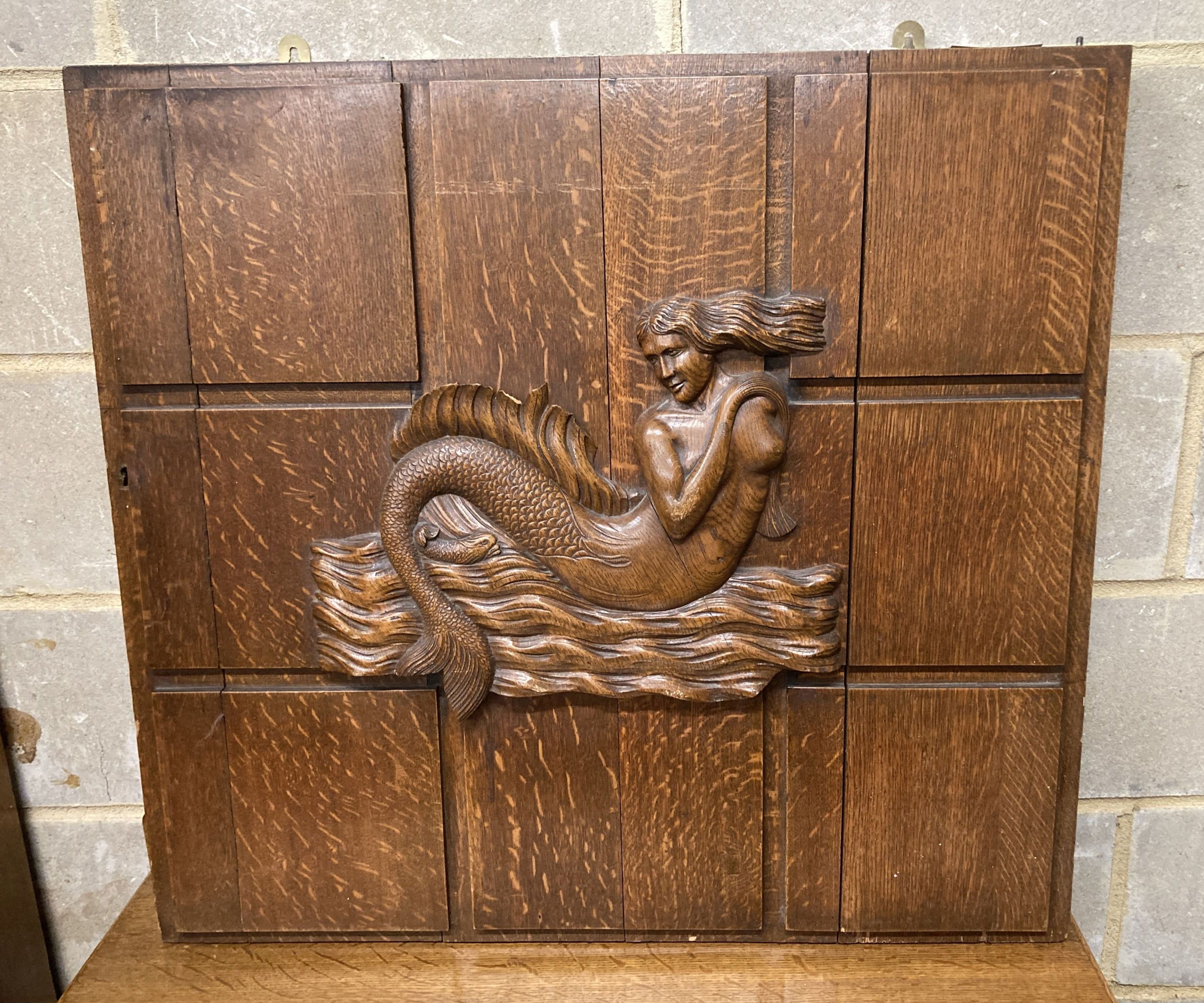 A mid 20th century rectangular oak panel carved with a mermaid formerly a cabinet door, width 81cm, depth 74cm